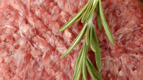 raw burger meat with rosemary slowly rotates.