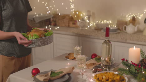 unrecognizable woman putting roast chicken on christmas dinner table 4