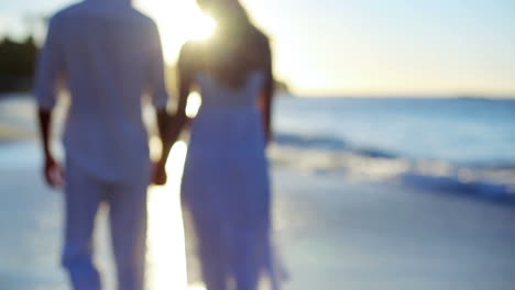 Man-taking-the-hand-of-his-girlfriend-before-they-walk-towards-the-sunset-on-the-beach