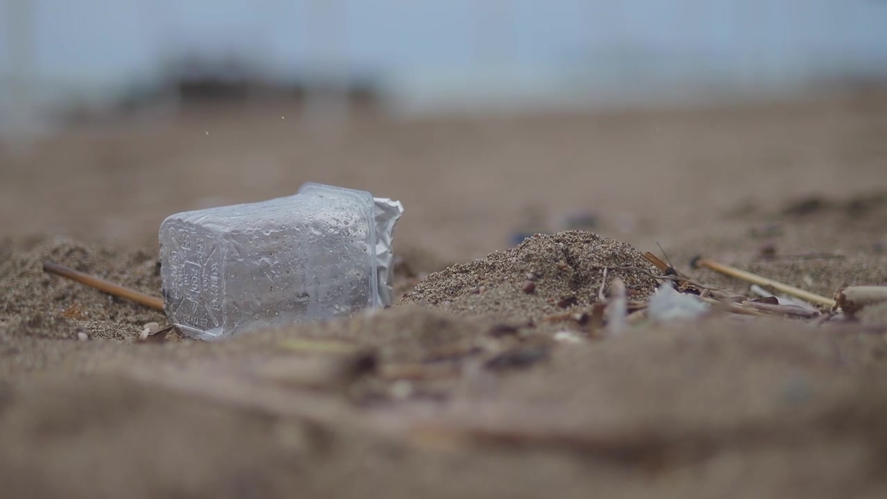Vasetto di yogurt di plastica scartato abbandonato su una spiaggia sabbiosa
