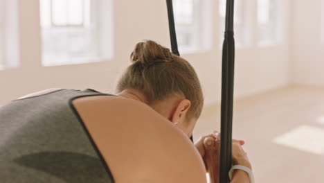 Aerial-Yoga-Frau-übt-Stehende-Kopf-an-Knie-Pose-In-Der-Hängematte-Und-Genießt-Einen-Gesunden-Fitness-Lebensstil,-Indem-Sie-Im-Studio-Bei-Sonnenaufgang-Meditation-Trainiert