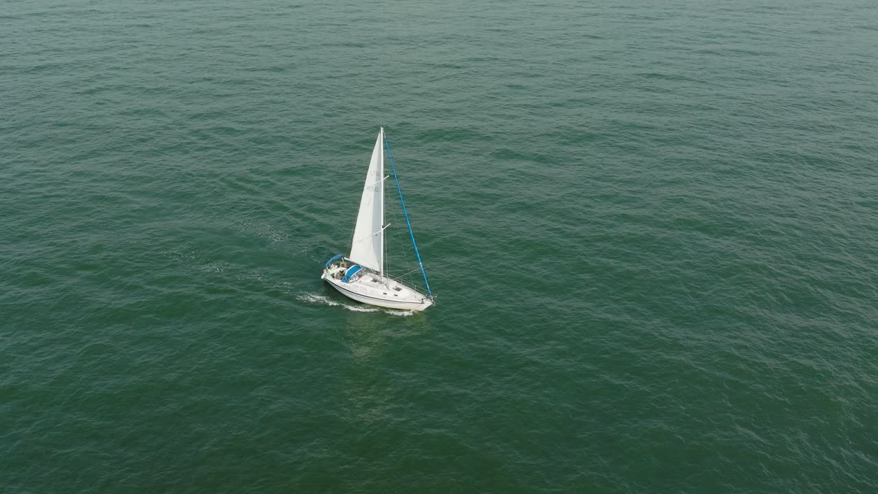 vista aérea estableciendo de un velero blanco en el mar báltico tranquilo, yate de vela blanco en medio del mar sin límites, día soleado de verano, ojo de pájaro de seguimiento amplio hecho disparo