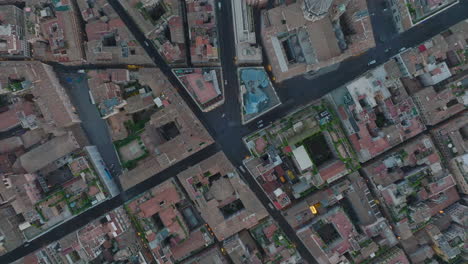 Overhead-shot-of-cars-driving-in-narrow-streets-between-historic-buildings-in-city-centre-at-twilight.-Rome,-Italy