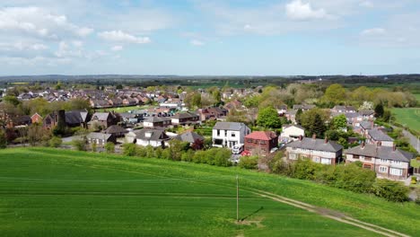 Aerial-view-rural-British-countryside-village-houses-surrounded-by-lush-farmland-fields,-Cheshire,-England