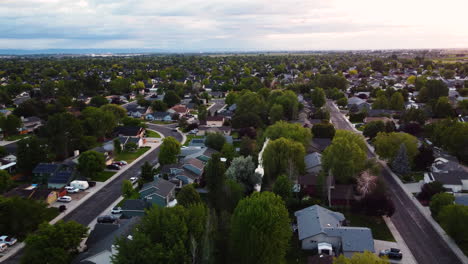 Vista-Aérea-Del-Paisaje-Que-Se-Eleva-Sobre-Una-Zona-Verde-Suburbana,-Al-Atardecer