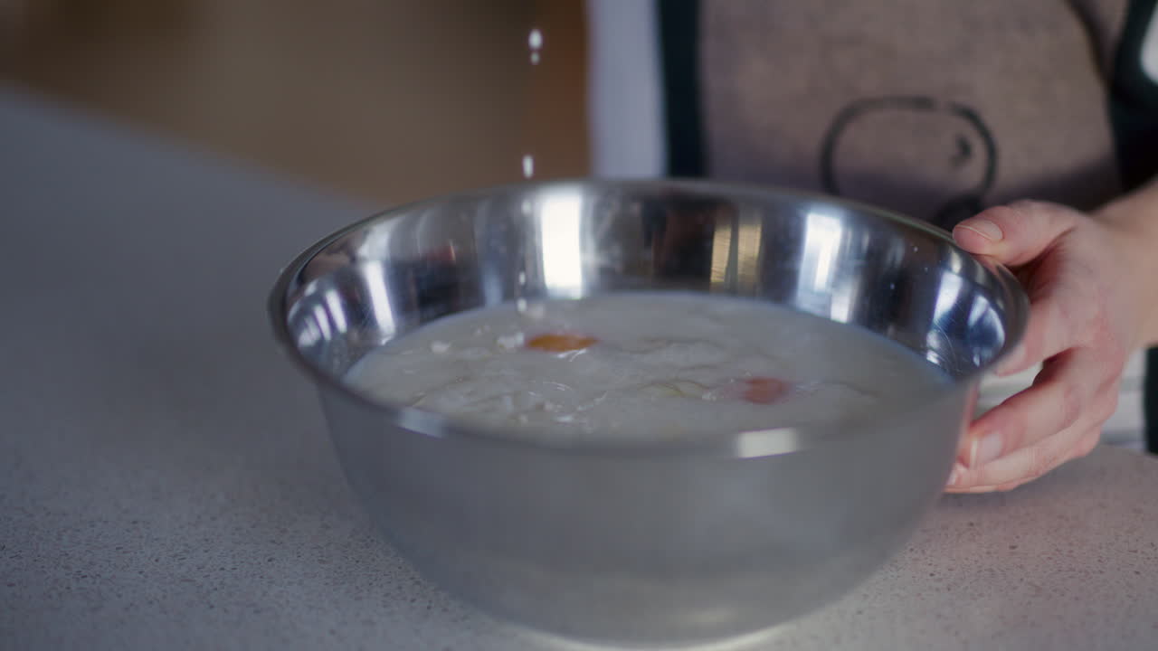 밀가루를 클로즈업으로 만드는 동안 그에 우유를 부어 넣는 것