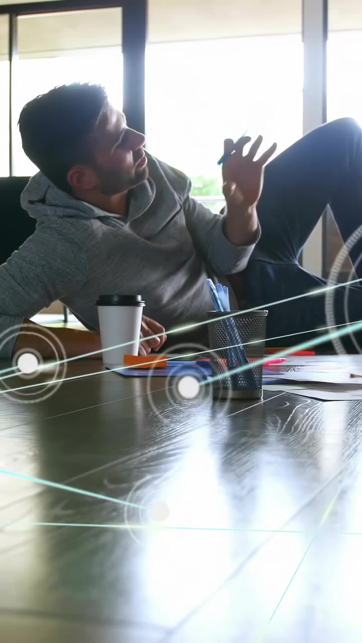 Vertical video: Man reclining on floor, holographic UI sweeping, raising hand organizing design