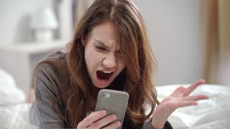 Mujer-Sorprendida-Viendo-Noticias-En-Video-En-Línea-En-Un-Teléfono-Móvil-Por-La-Mañana