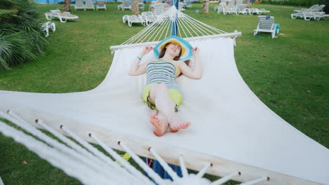 una chica brillante con ropa de colores fríos y un sombrero de ala ancha descansa en la costa del mar en un blanco