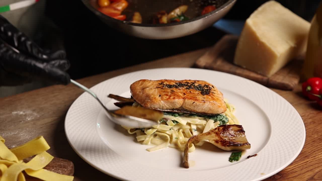 Chef che impiattano un piatto gourmet di salmone e pasta