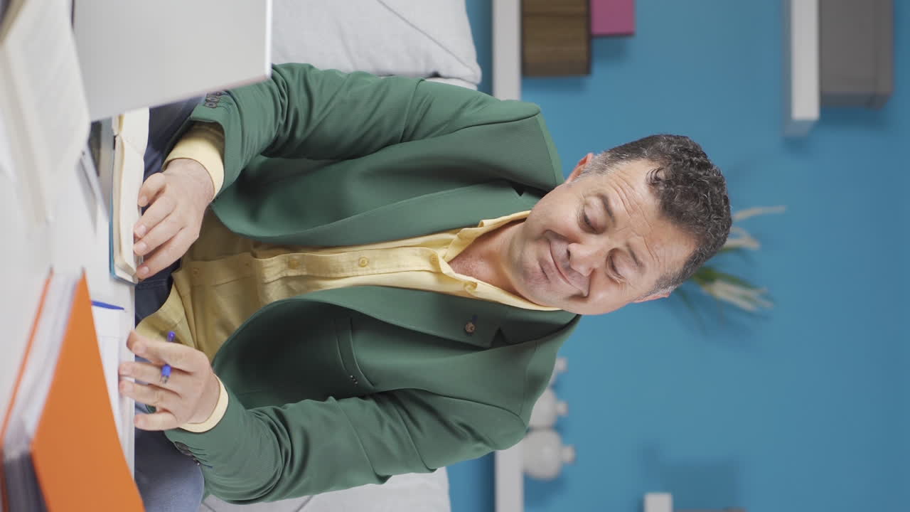 video vertical de un anciano trabajador de la oficina en casa trabajando relajado y pacíficamente.