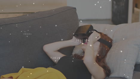 mujer acostada en un sofá agitando las manos mientras usa un auricular de realidad virtual