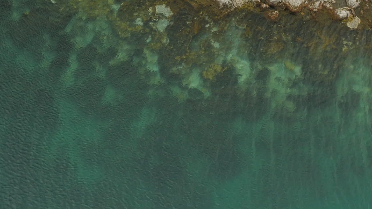 Incredibile vista aerea a volo d'uccello di acqua cristallina lungo la riva del Lago Giurassico, Argentina.