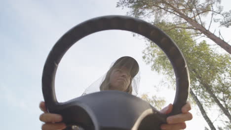 Lady-with-mosquito-head-net-mows-lawn-with-ride-on-mower,-annoyed-by-mosquitoes