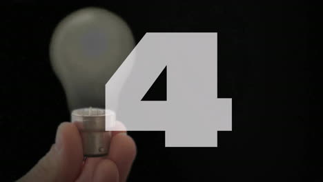 hand holding small light bulb with number 5 animation over blurred background