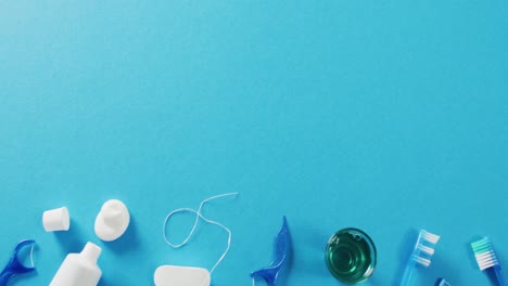 Video-of-close-up-of-toothbrush-and-floss-on-blue-background