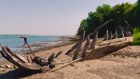 a 4k drone shot in ireland and at fethard saltmills beach wexford of an abandoned wooden boat hull