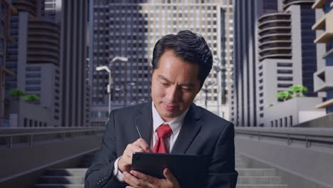 businessman using tablet in front of skyscrapers