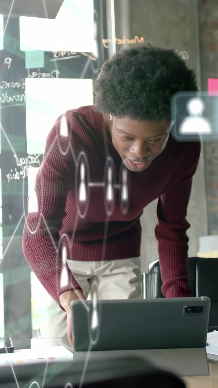 Vertical video: Man leaning over table, tapping tablet and revealing AR UI on glass for tech review