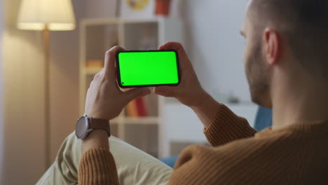 el participante en el chat de video está mirando la pantalla del teléfono inteligente y asintiendo con la cabeza a la pantalla verde para el montaje comunicándose por internet para trabajar