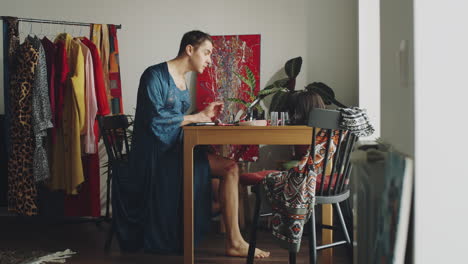 transgender man walking in room and applying makeup