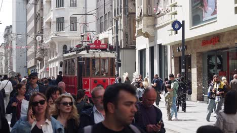 a red vintage tram travels through a bustling street in istanbul, turkey.