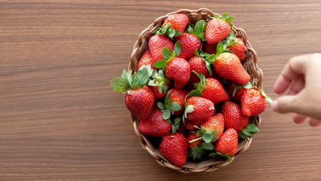 hand picking strawberries from a basket