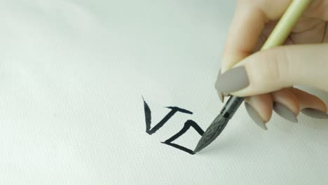 woman practicing calligraphy, writing the letter v