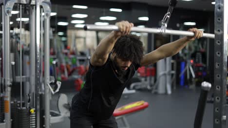 joven haciendo ejercicio de tracción lateral en el gimnasio para los músculos de la espalda, movimiento lento