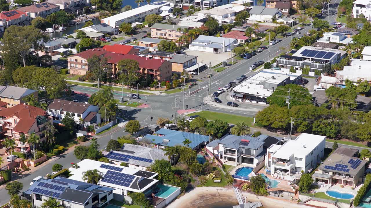 Drone footage captures suburban roads, luxury homes, and traffic under bright daylight, showcasing a vibrant neighborhood from above