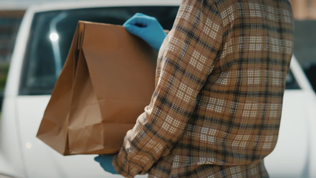 el empleado del servicio de entrega tiene bolsas de papel con comida en un fondo de furgoneta blanca