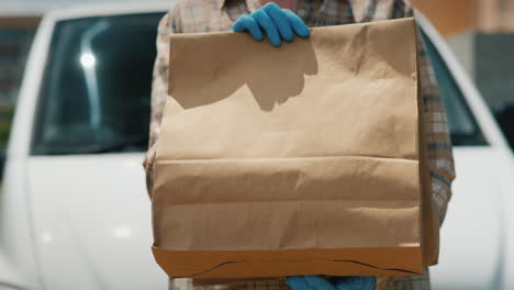 Empleado-Del-Servicio-De-Entrega-Tiene-Bolsas-De-Papel-Con-Comida-Sobre-Un-Fondo-De-Camioneta-Blanca