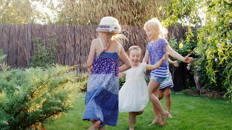 Vier-Sorglose-Kinder-Lachen-Im-Garten-Während-Mit-Wasserbächen