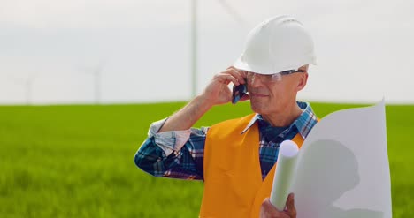ingeniero enojado hablando por teléfono móvil en la granja de molinos de viento