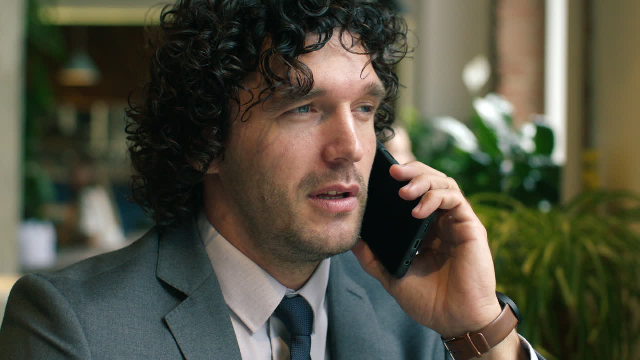 Professional Businessman Speaking during Phone Call in Modern Cafe