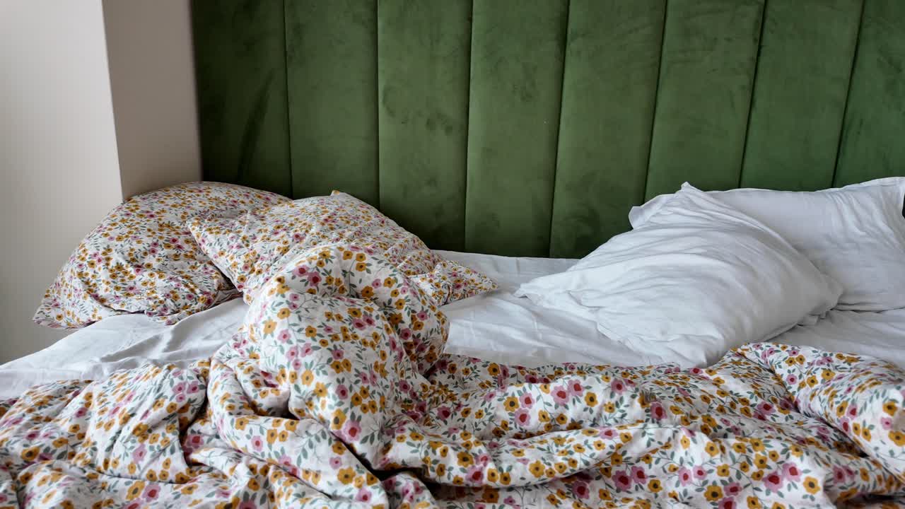 A bed with floral bedding and green headboard