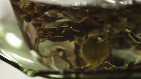 chinese green tea leaves infused in hot water inside traditional glass bowl