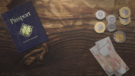 mesa de madera con pasaporte de viaje y moneda de metal y papel moneda