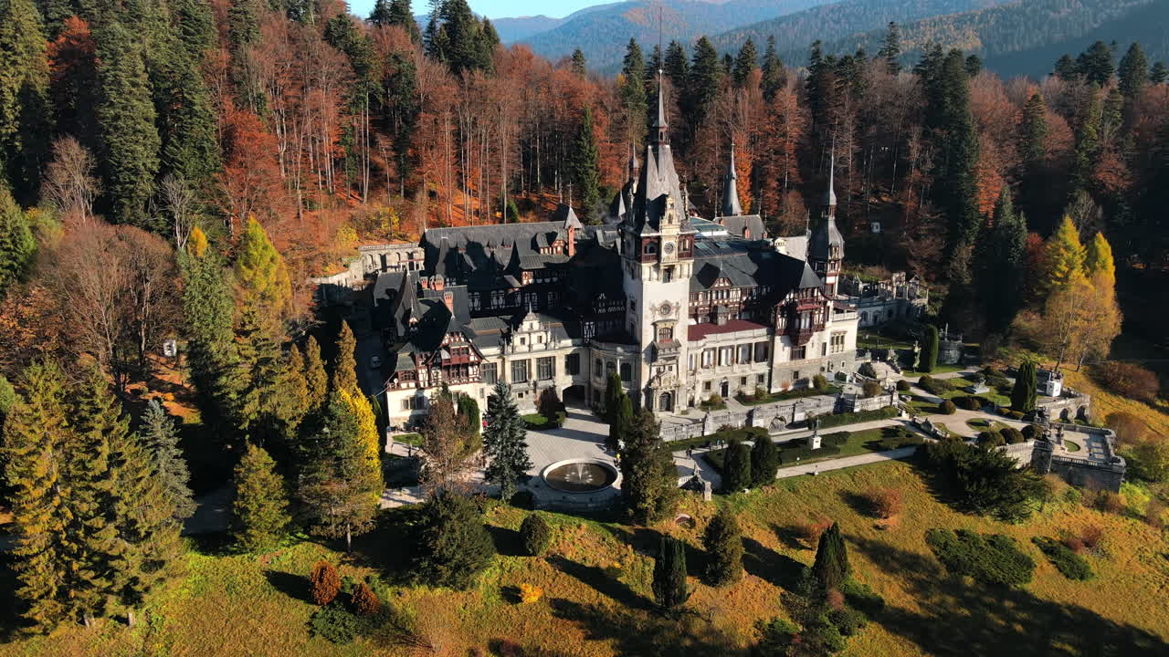 Aerial drone view of The Peles Castle in Romania. Castle with gardens in Carpathians, forest around it, tourists