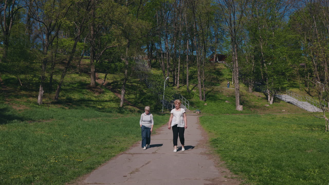 Two senior women walking in a park on a sunny day