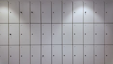 close up of a wall of numbered office lockers, some showing keys and keyholes, providing secure storage for employees