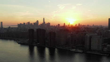 Fly-along-waterfront.-Romantic-colourful-sunset-above-large-city.-Silhouettes-of-downtown-skyscrapers.-Manhattan,-New-York-City,-USA