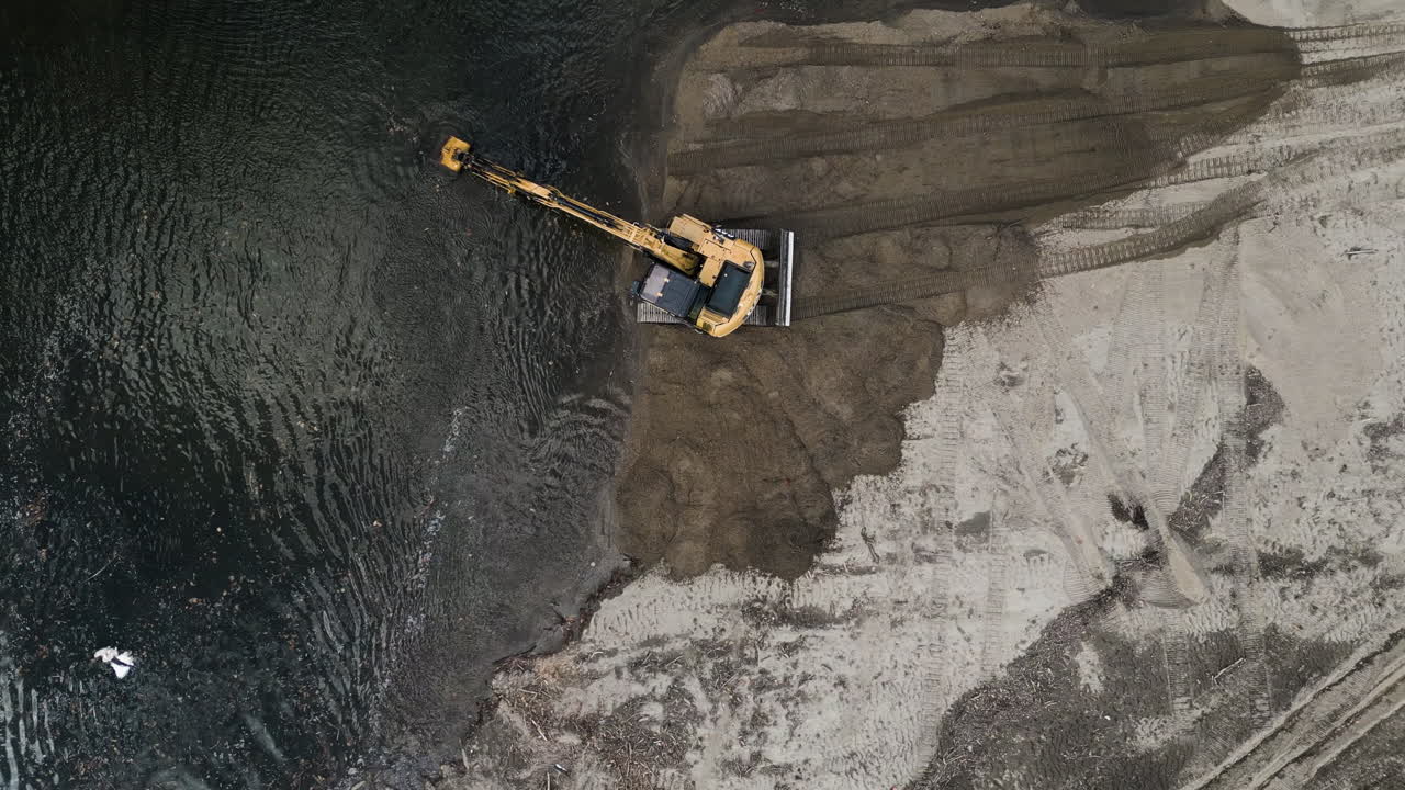 el dron se eleva para revelar una excavadora que elimina sedimentos de un río que fluye por la orilla arenosa