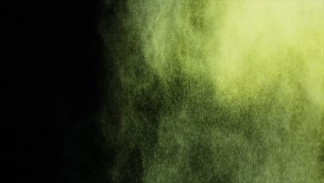 green and yellow dust powder blowing against black background