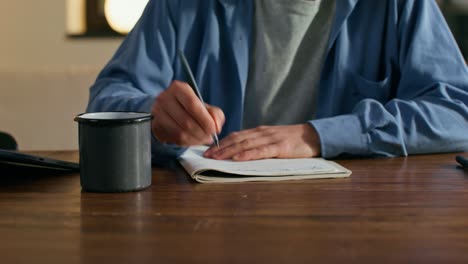 person writing in a notebook at a desk