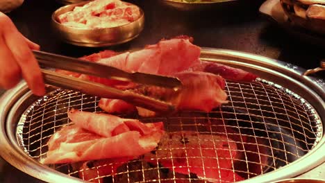 tongs flipping meat on a barbecue grill