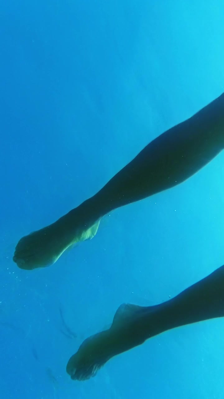 Nuotatore che esegue la rana in un mare blu cristallino.
