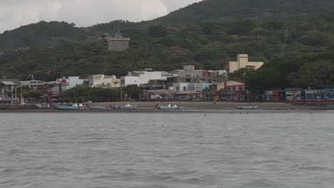 Traditional-fishing-boats-with-long-curved-bows-beached-on-sand-at-Bali-district,-Taipei