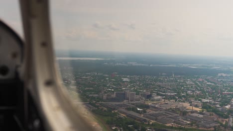 airplane window view air traveling, flying above city town buildings, day