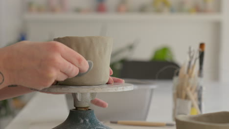 working designs into soft clay with a specialized tool, showcasing artisan's delicate touch